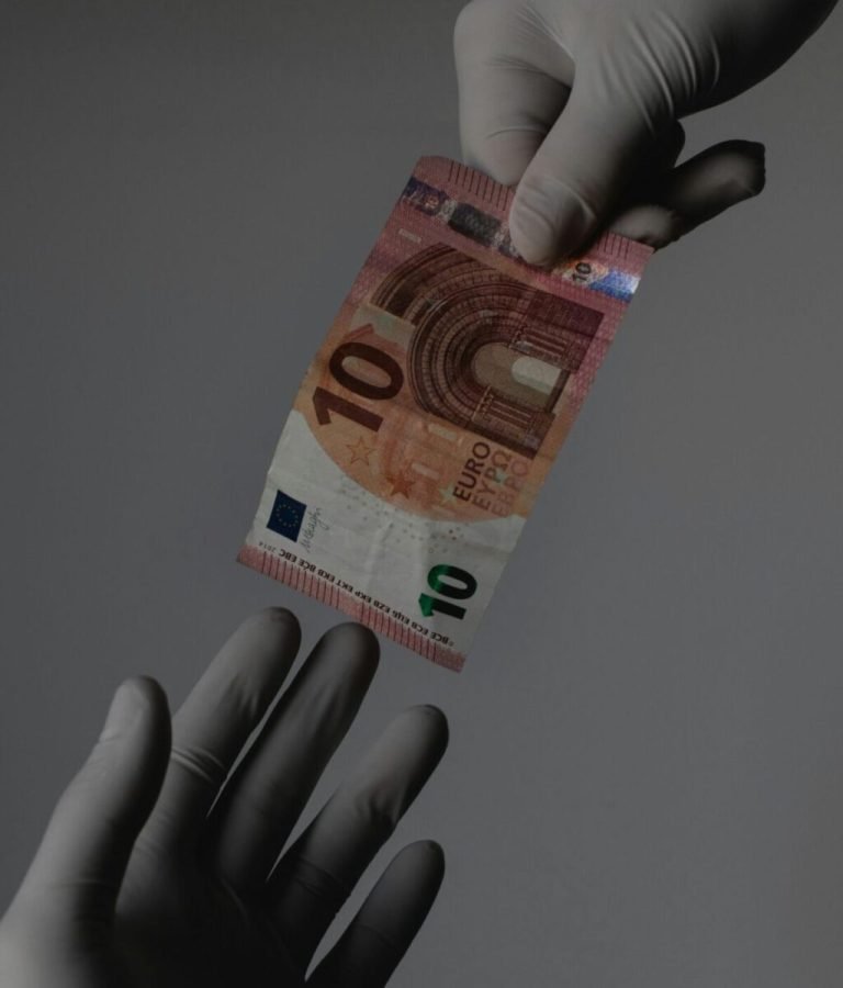 La imagen muestra una mano con guantes que ofrecen alta resistencia y seguridad entregando un billete de 10 euros a otra mano. Representación gráfica de aval financiero.